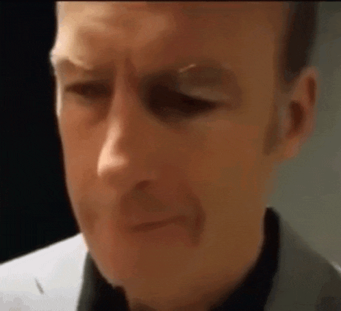 a close up of a man 's face with a black shirt and a white shirt .
