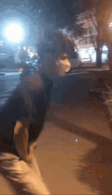 a man wearing a face mask is walking down a street at night