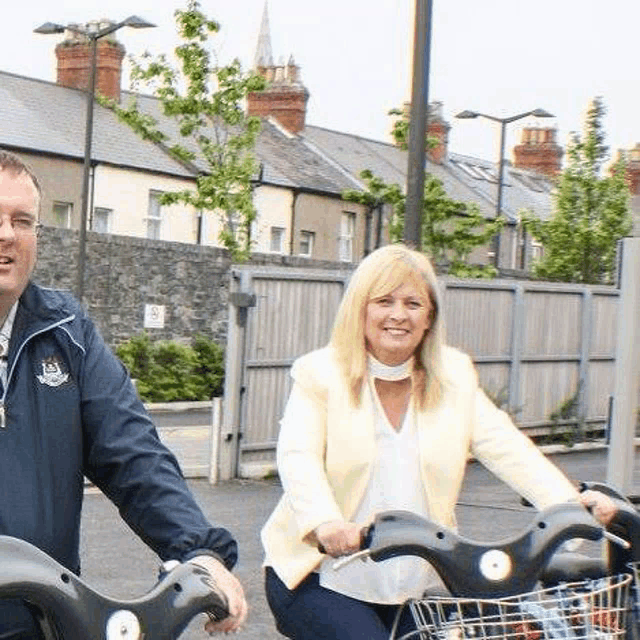 a man and a woman are riding bicycles down the street .