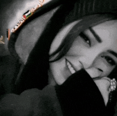 a black and white photo of a woman wearing a hooded jacket and smiling .