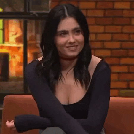 a woman is sitting on a couch with her arms crossed and making a face .