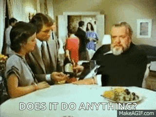 a group of people are sitting at a table with a plate of food and a man is smoking a cigarette .
