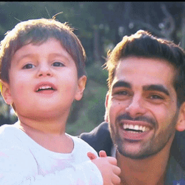 a man is holding a little boy in his arms and they are smiling for the camera