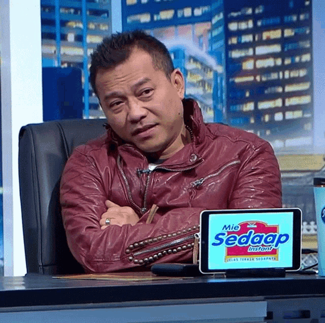 a man is sitting at a desk with a tablet that says mie sedaap instant