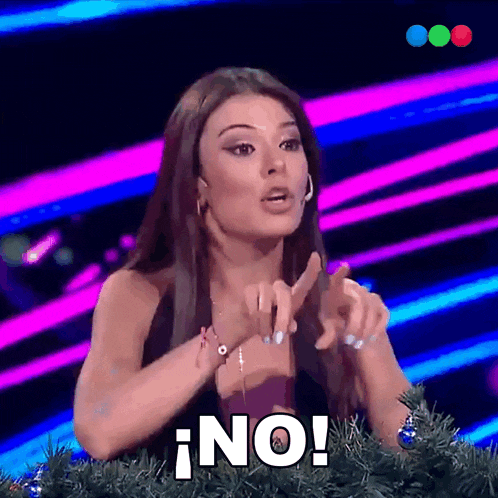 a woman sitting in front of a christmas tree has the word no written on her face