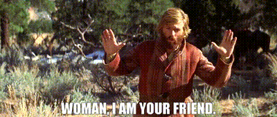 a man with a beard is standing in a field with his arms outstretched and says woman i am your friend