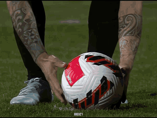 a person with a tattoo on their arm is holding a soccer ball with the number 21 on it