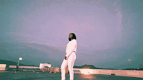 a woman in a white outfit is standing on a rooftop .