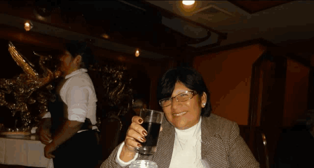 a woman with red nails is holding a glass of wine and smiling