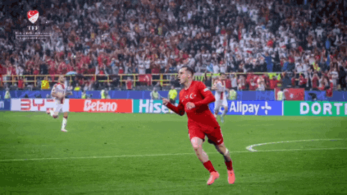 a soccer player celebrates a goal on a field with a betano ad behind him