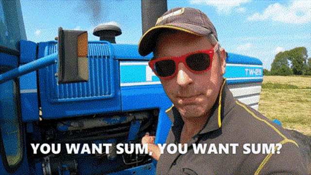 a man wearing sunglasses and a hat is standing in front of a blue tractor and says you want sum you want sum