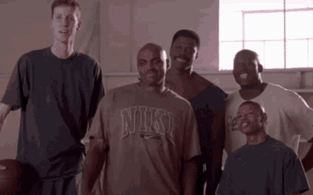 a group of men are posing for a picture and one of them is wearing a nike t-shirt