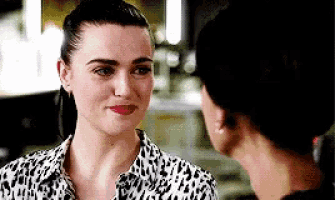 two women are looking at each other and smiling . one of the women is wearing a leopard print shirt .