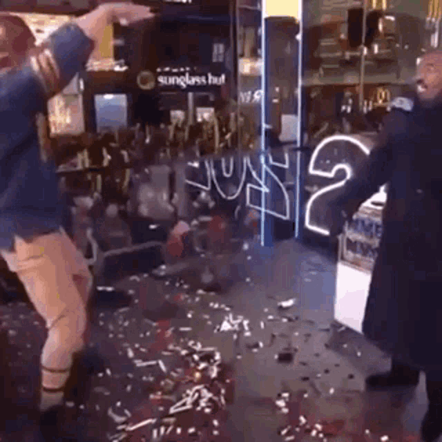 two people are dancing in front of a store that says sunglasses hut