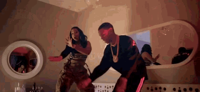 a man and woman are dancing in front of a mirror in a room .