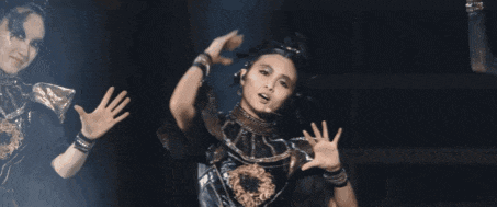 a woman in a black and gold outfit is dancing on a stage