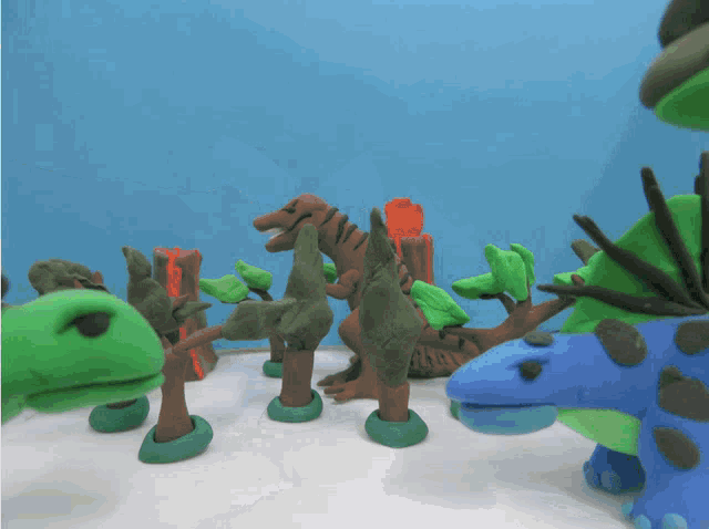 a group of clay dinosaurs with trees and a volcano