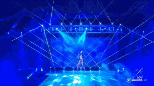 a woman is dancing on a stage surrounded by blue lights and a sign that says bt sports live