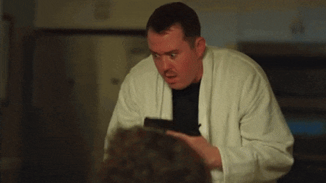 a man in a white robe is holding a gun in front of a woman .