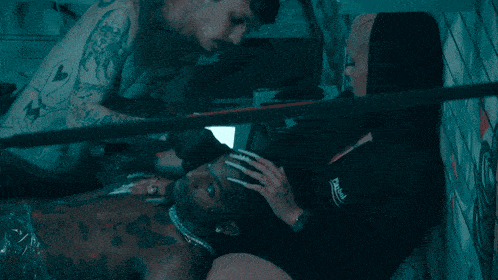 a man with a tattoo on his arm is laying on another man
