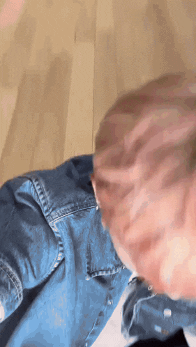 a close up of a person 's head with a denim shirt on