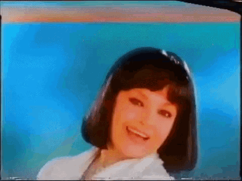a woman in a wig is smiling and looking at the camera .