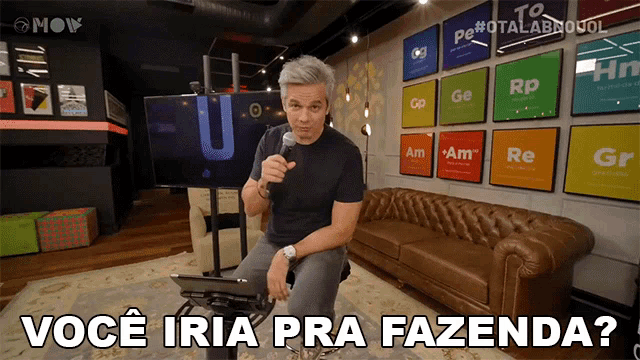 a man is sitting in front of a couch holding a microphone and the words você iria pra fazenda