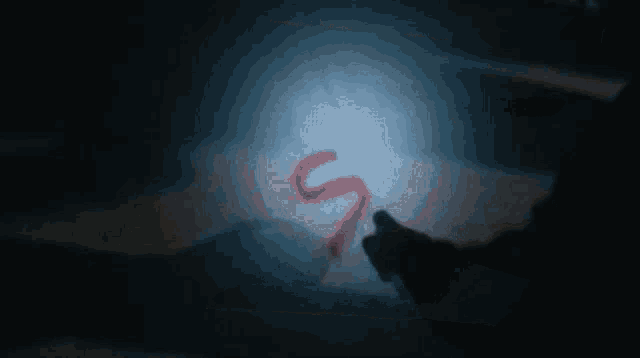 a person holding a flashlight with the letter s written in red