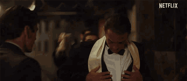 a man in a tuxedo is covering his face with a napkin and a netflix logo is visible in the background