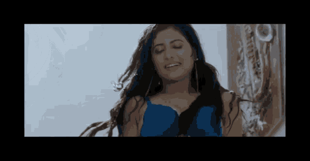 a woman in a blue bra is standing in front of a wall .