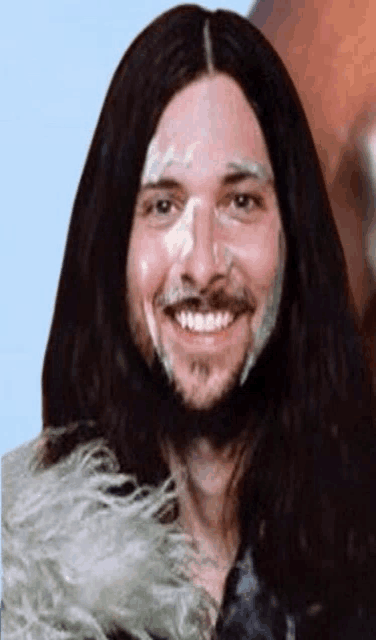 a man with long hair and a beard smiles