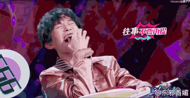 a man in a pink jacket is laughing with chinese writing on the bottom