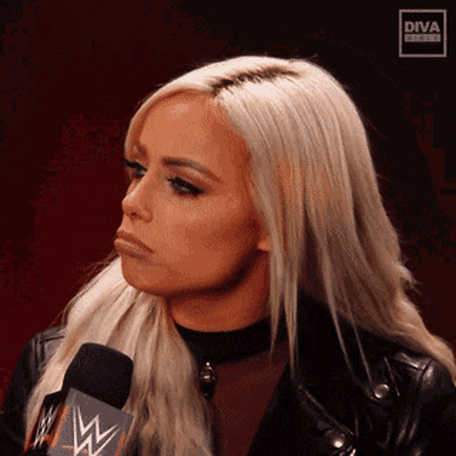 a woman in a black leather jacket is talking into a microphone with a diva logo on it