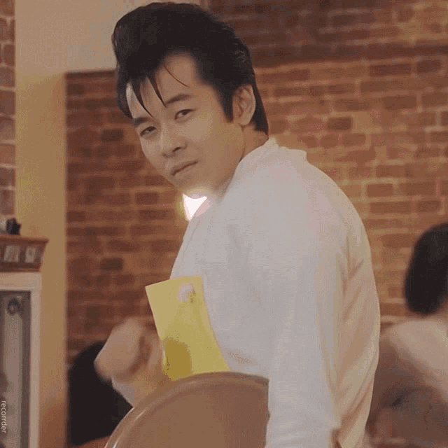 a man in a white shirt holds a yellow folder