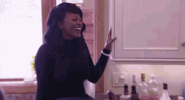 a woman in a black sweater is standing in a kitchen .