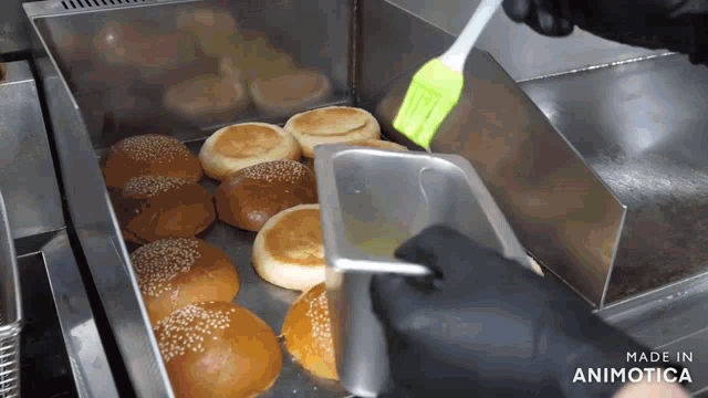 a bunch of hamburger buns are being brushed with a green brush and made in animatica