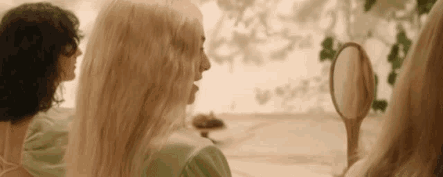 a woman is looking at her hair in a mirror .