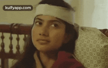a woman with a bandage on her head is sitting in a chair .