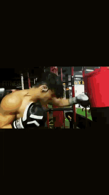 a man wearing boxing gloves in a gym with the word fitness on the bottom
