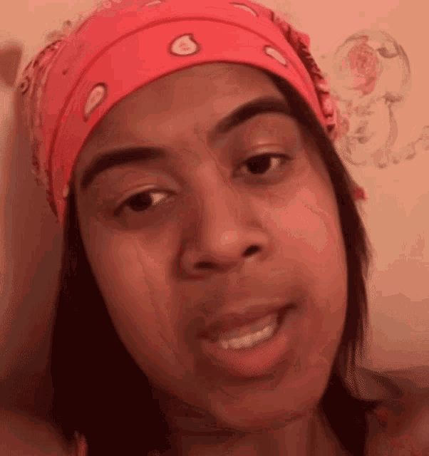 a woman wearing a pink bandana on her head looks at the camera
