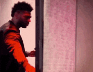 a man in a red jacket is opening a door in a dark room .