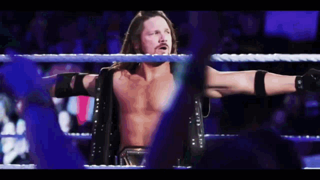 a shirtless wrestler is standing in a wrestling ring with his arms outstretched