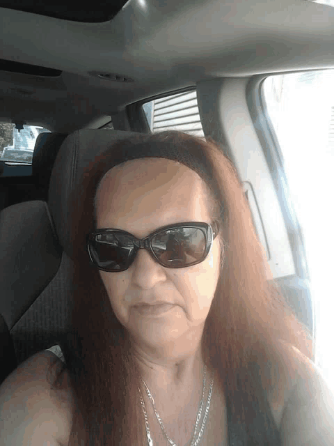 a woman wearing sunglasses and a headband is sitting in the back seat of a car