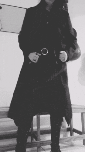 a black and white photo of a person in a long black coat