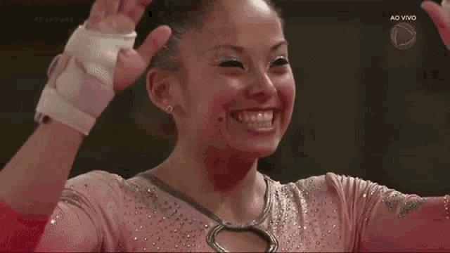 a female gymnast is smiling with her hands in the air