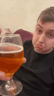 a man is holding a glass of beer in his hand .