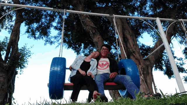 a man and a woman are sitting on a tire swing with a shirt that says jeep on it