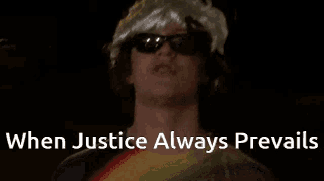 a man wearing sunglasses and a hat is standing in the dark with the words `` when justice always prevails '' above him .