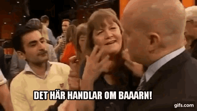 a man is touching a woman 's face in a crowd of people while a woman looks on .