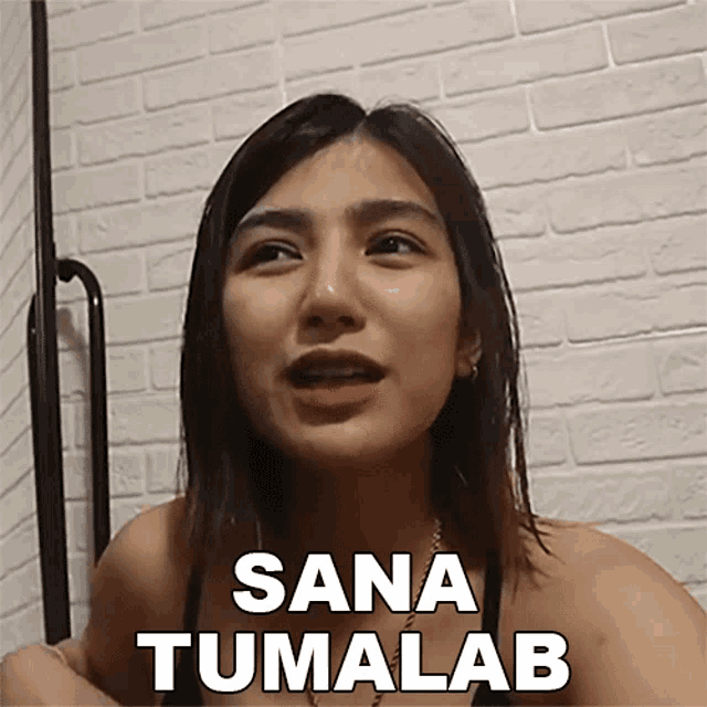 a woman says sana tumalab in front of a brick wall